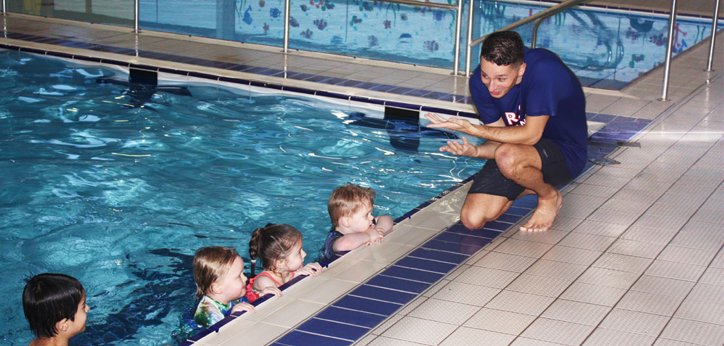 Swimming teacher on side with pupils in water